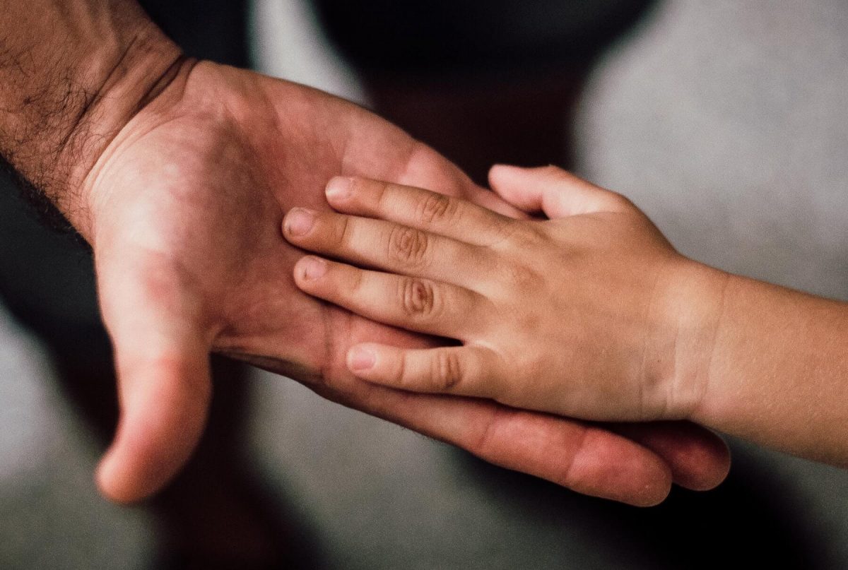 A picture of hope and help as and adult holds a child's hand.